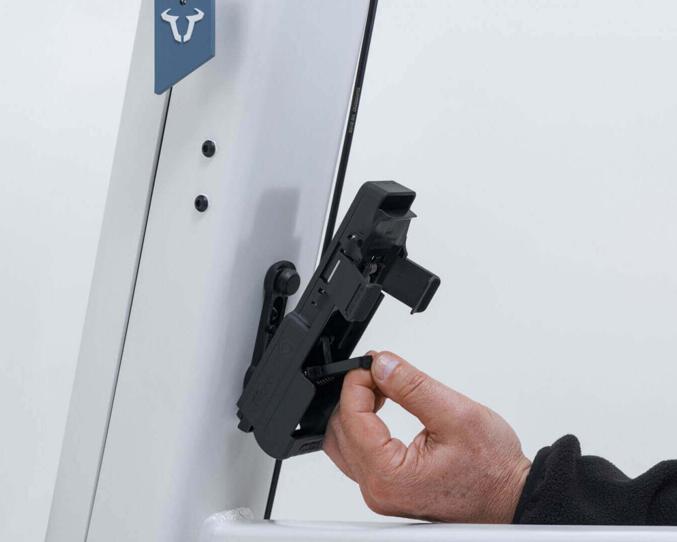 ABUS Bordo 6000K Faltschloss mounted on a bike frame with hand inserting a key.