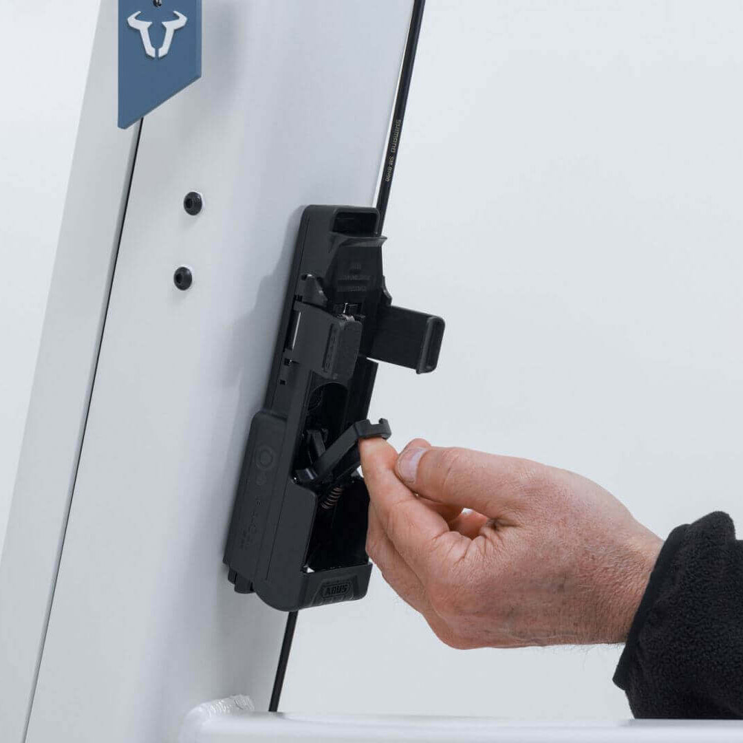 Hand attaching ABUS Bordo 6000K Faltschloss to Fidlock mount on a bike frame.