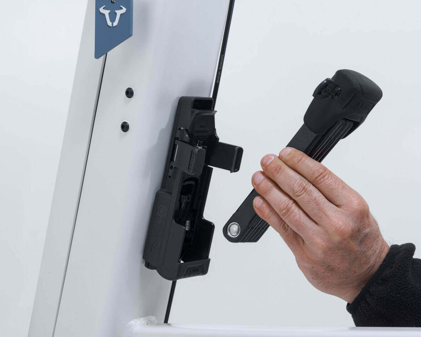 Hand attaching ABUS Bordo 6000K Faltschloss to Fidlock mount on VIA E-Lastenrad for secure locking.