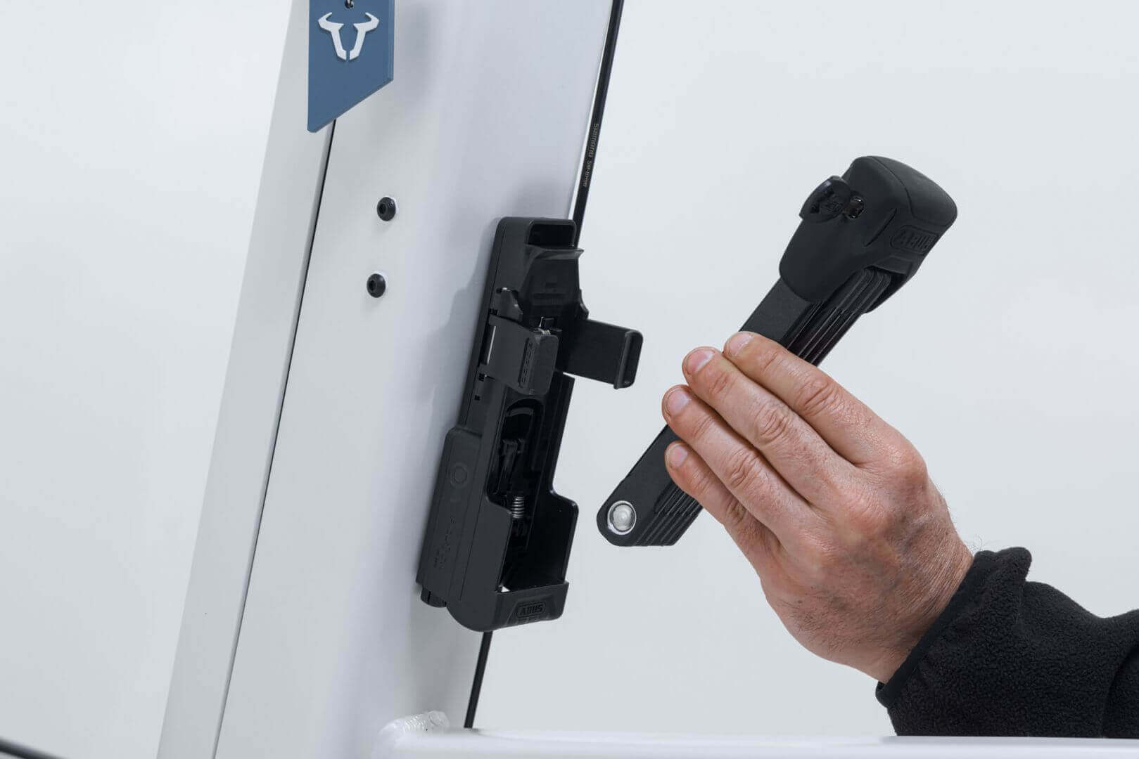 Hand attaching ABUS Bordo 6000K Faltschloss to Fidlock mount on VIA E-Lastenrad for secure locking.